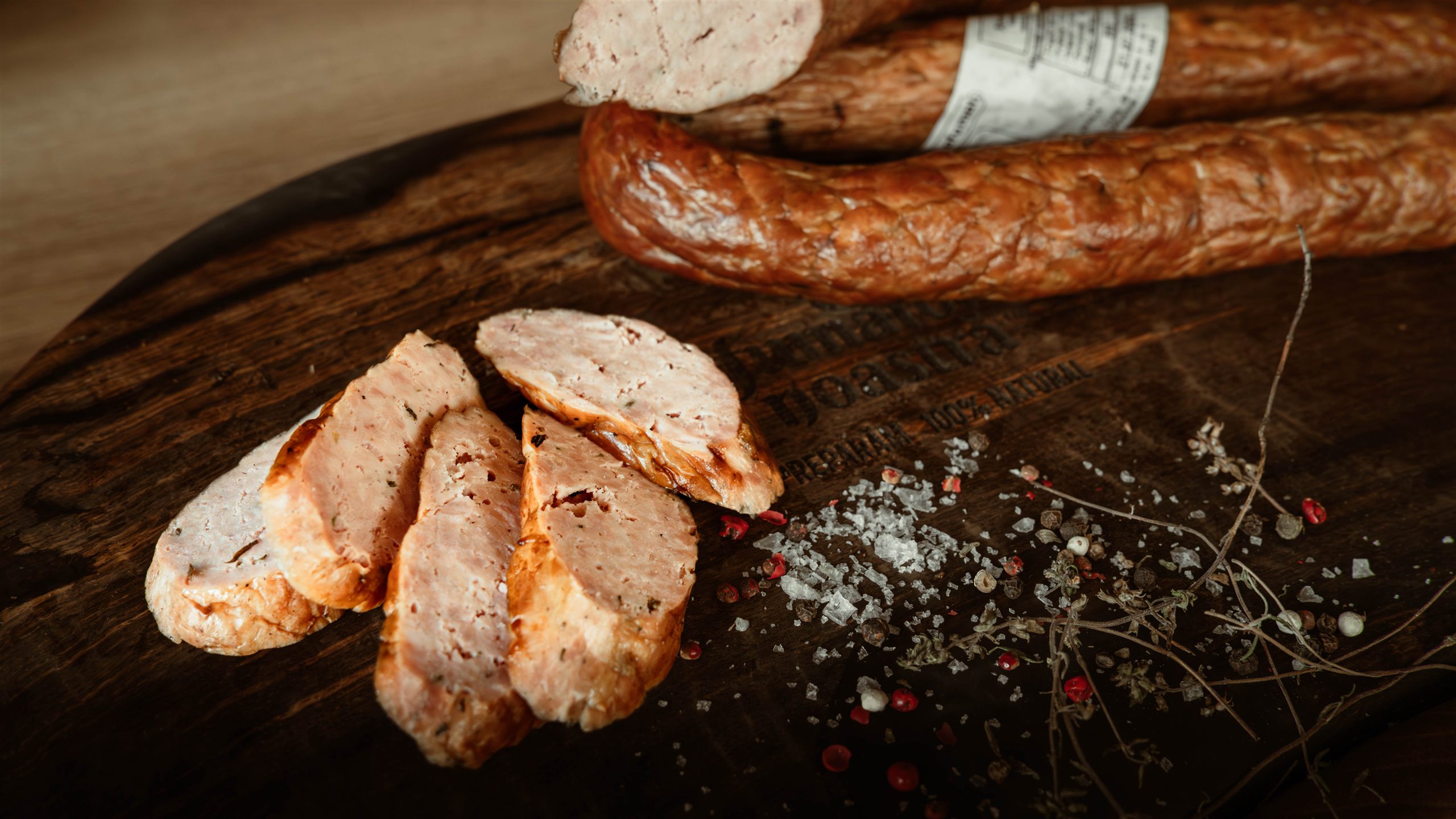 Carnati afumati de porc feliati pe fund de lemn, preparati 100% natural