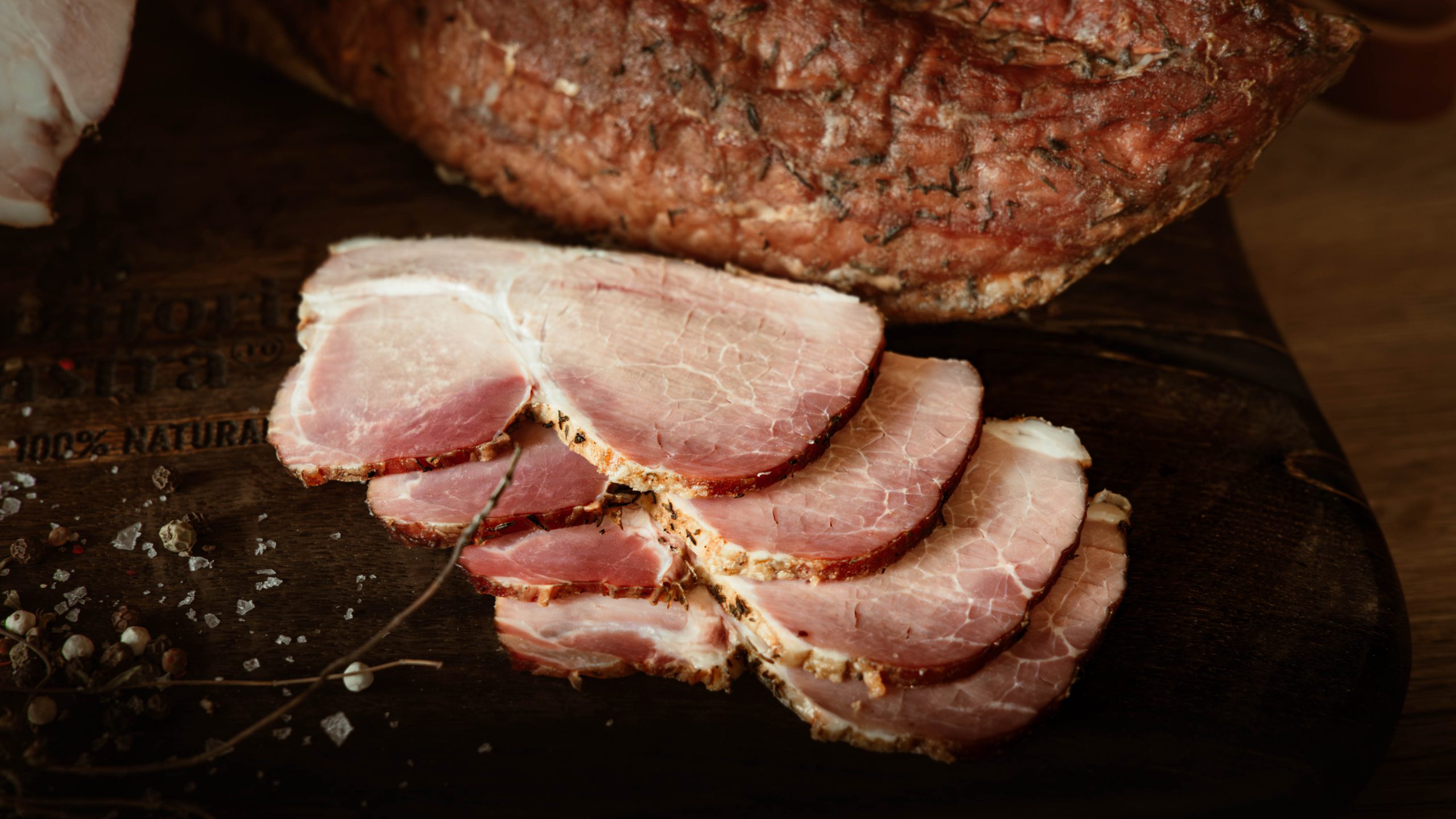 Pastrama de porc afumata taiata felii subtiri pe fund de lemn