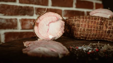 Pastrama de vitel de lapte afumata, in plasa, taiata felii pe fund de lemn