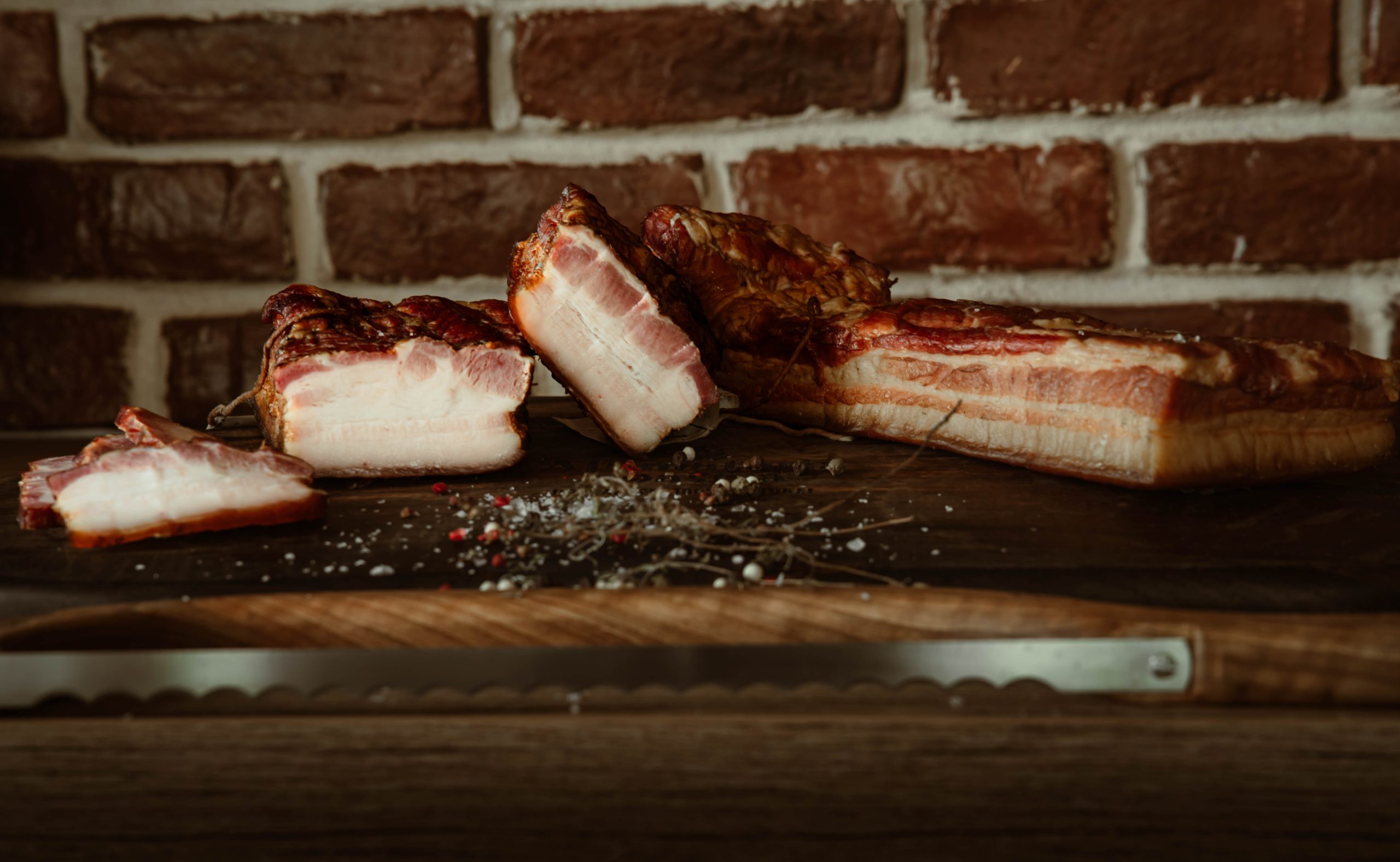 Slaninuta de porc afumata natural cu lemn de fag si cires, feliata pe fund de lemn